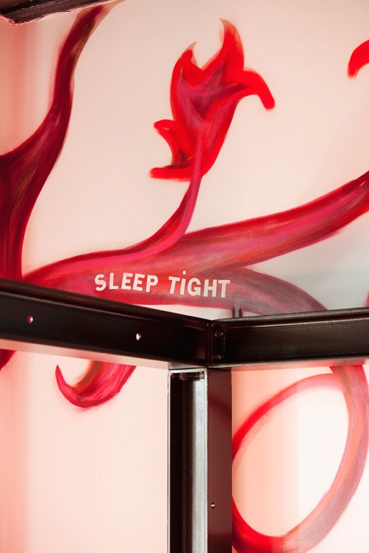 Steel profile four poster bed frame and imaginative mural on wall with motto 'Sleep tight'
