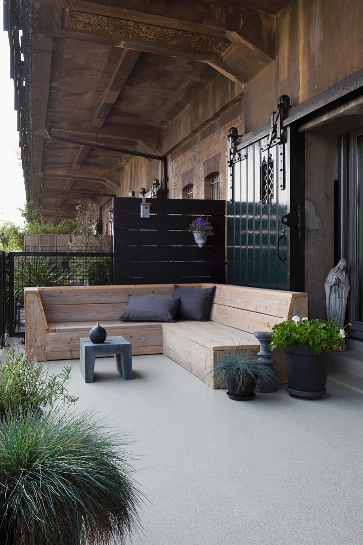 Rustikale Holz Eckbank und Pflanzen auf Terrasse vor Loft mit industriellem Charme