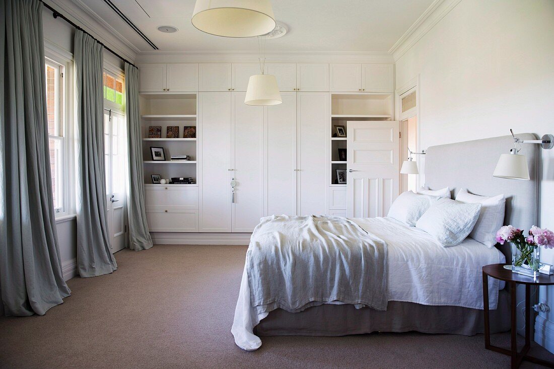 Bright gray and white bedroom with built-in wardrobe and double bed with headboard