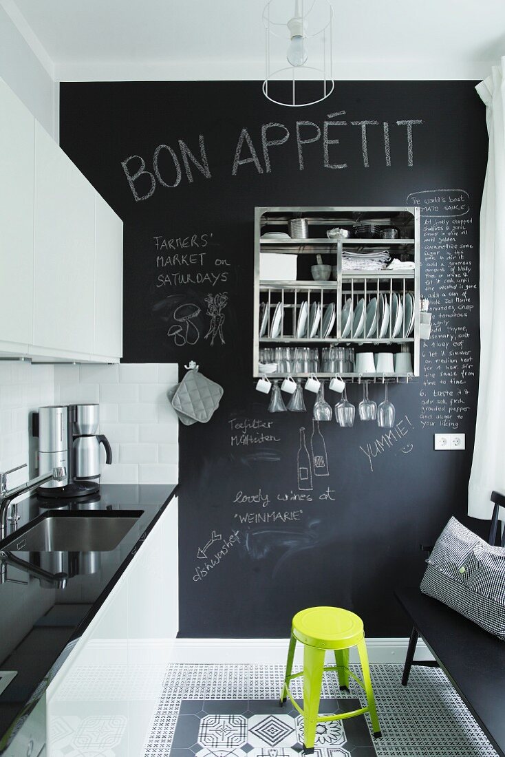 Blick in Küche mit glänzender Schrankfront, dekorativen schwarz-weissen Bodenfliesen und Tafelwand
