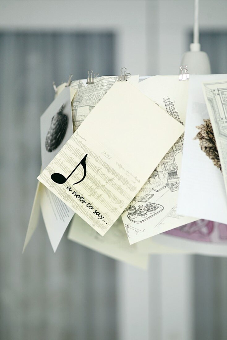 Pendant lamp with illustrations and cards clipped to lampshade