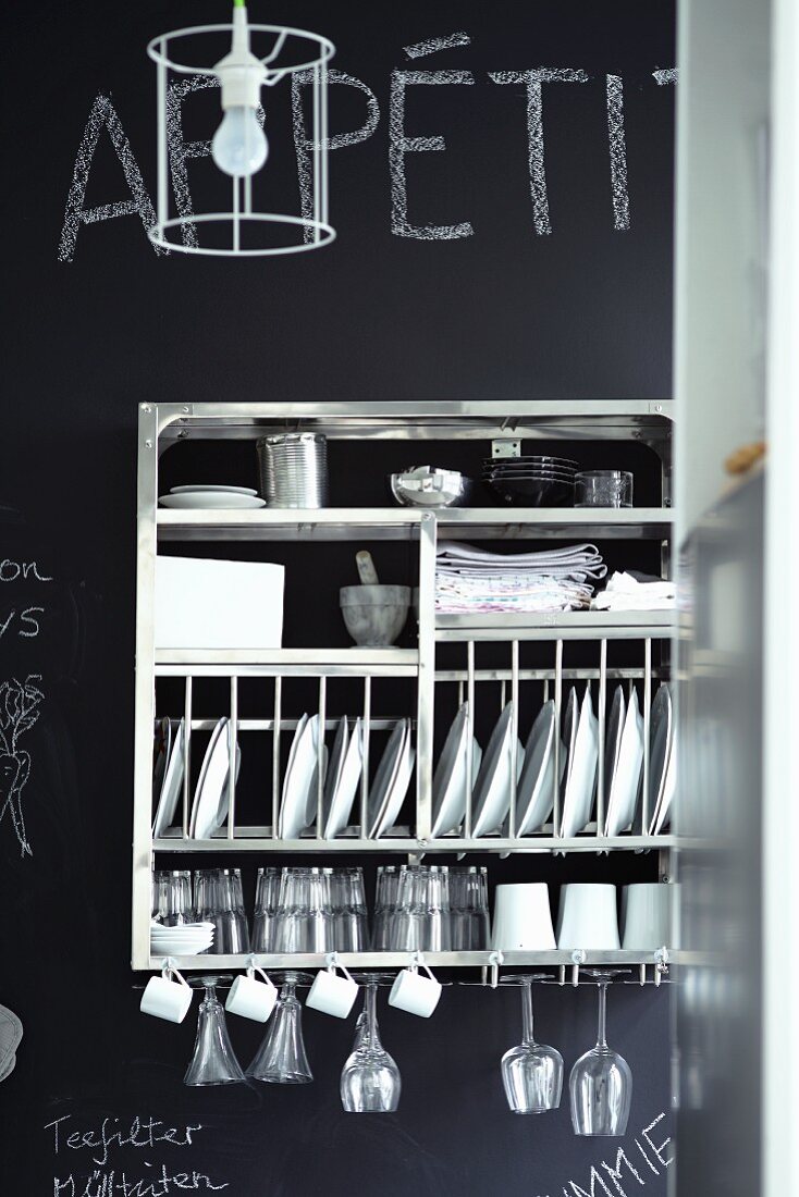 Stainless steel, wall-mounted crockery rack on chalkboard wall