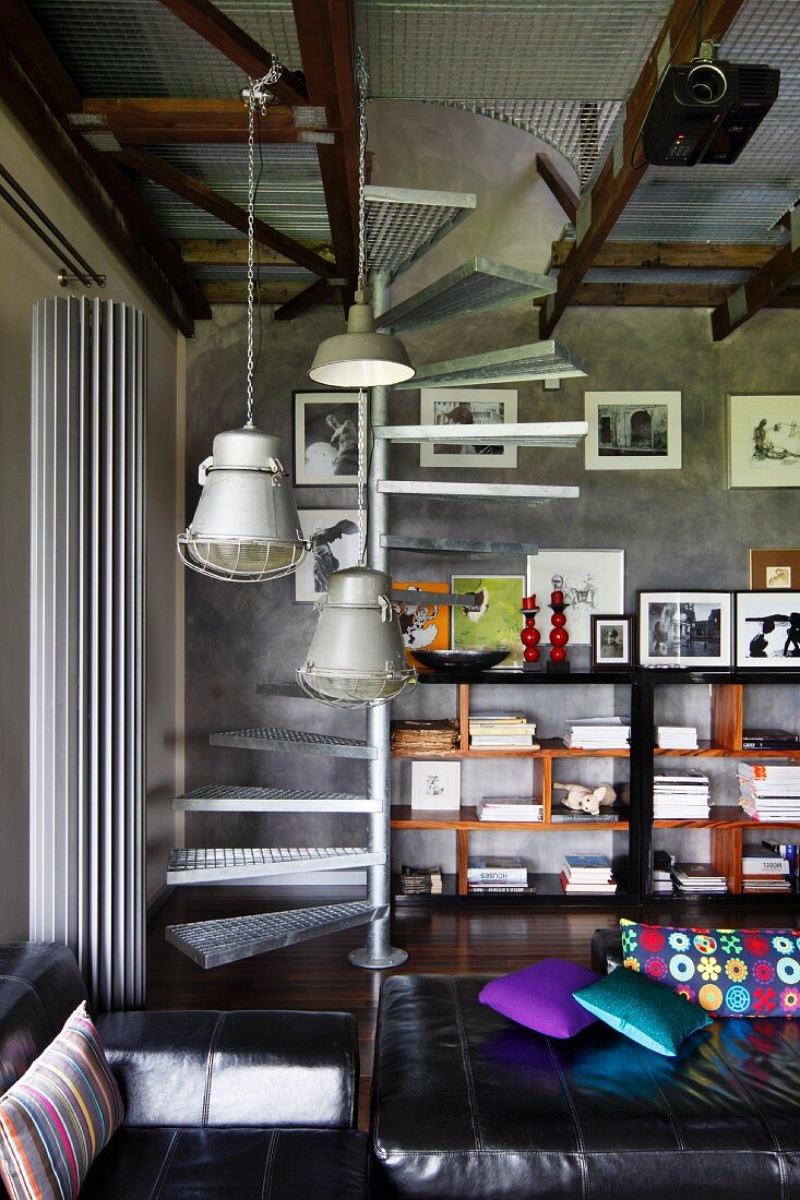 Retro, industrial pendant lamps in lounge area, galvanised, metal spiral staircase in background next to half-height shelving against grey wall