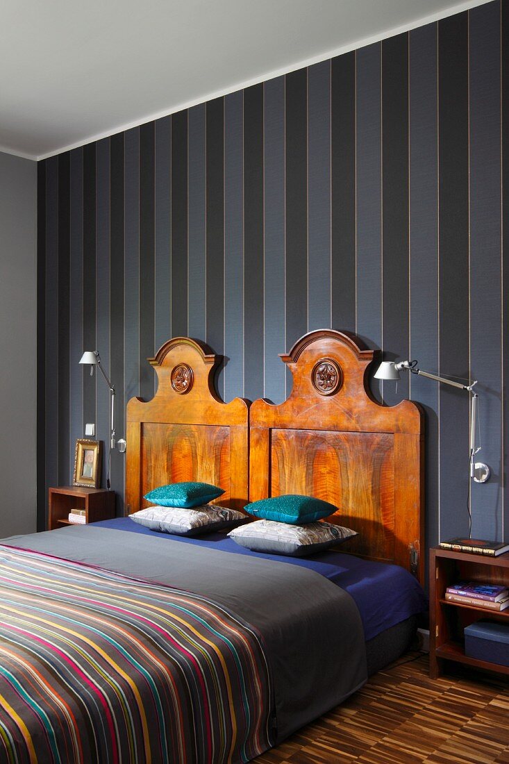 Bed with antique wooden headboards against striped wallpaper