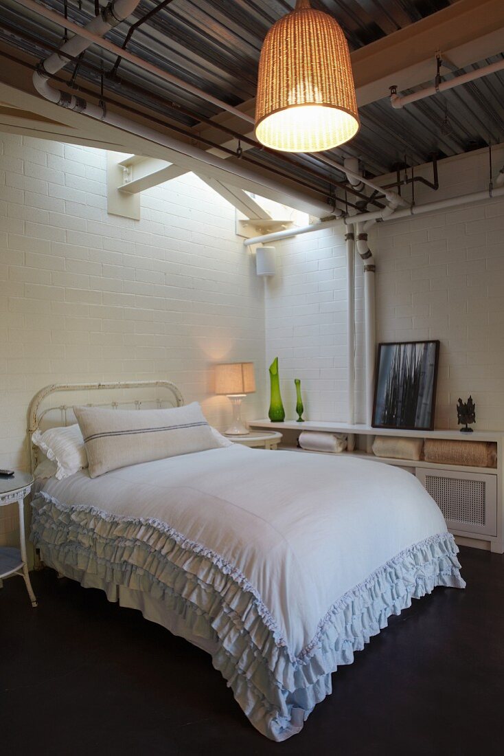 Doppelbett mit Rüschen Tagesdecke in schlichtem Zimmer, Pendelleuchte mit Korb Schirm an Trapezblech Decke