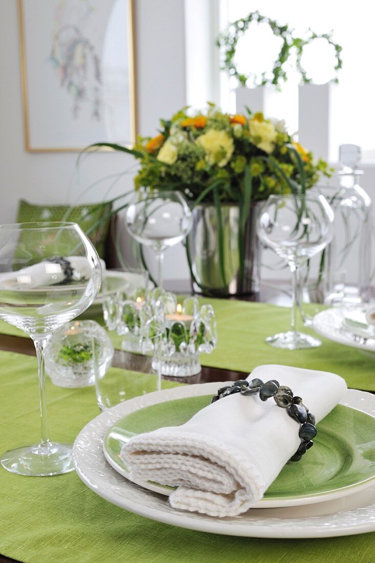 Festlich gedeckter Tisch - Stoffserviette mit Ring auf grünem Teller und farblich passender Tischläufer