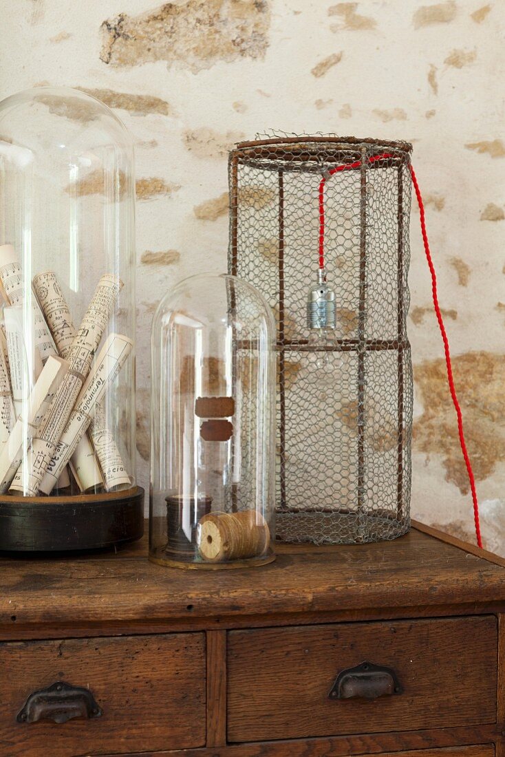 Table lamp with wire mesh lampshade next to objects under glass domes