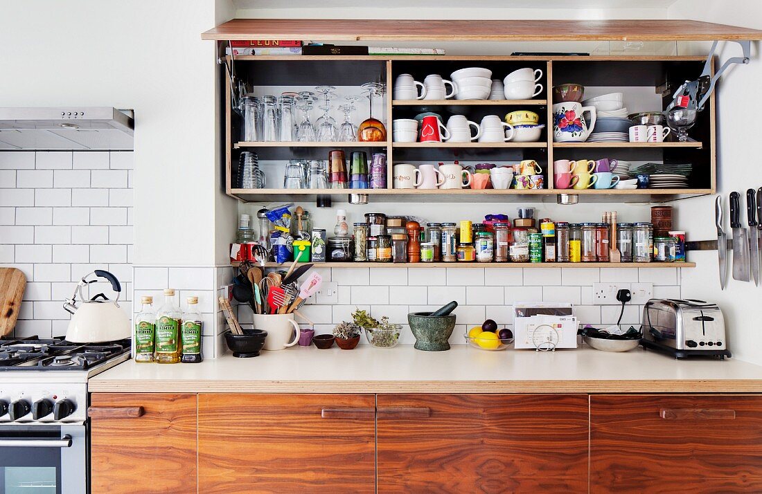 Küchenhängeschrank mit geöffneter Klappfront, darunter Gewürzbord und Unterschrank aus recyceltem Holz