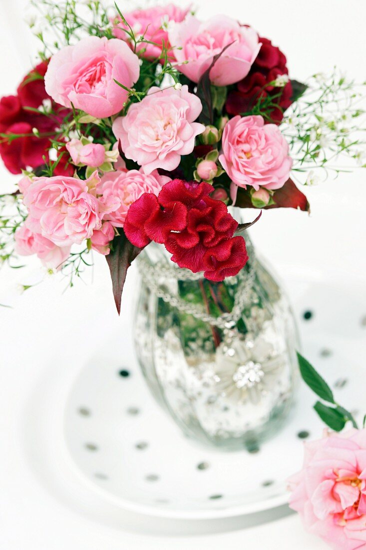 Bouquet of roses with cockscomb and gypsophila in silvered glass vase