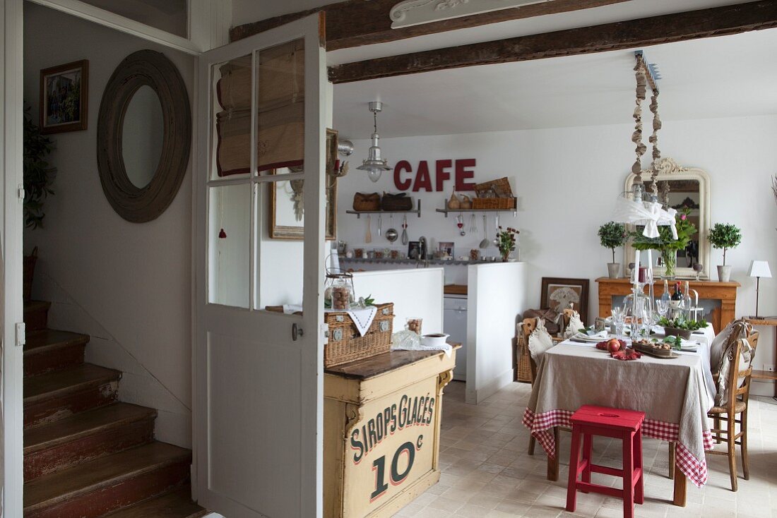 Festlich gedeckter Esstisch in offener Landhausküche und Blick auf Vintage-Treppenaufgang