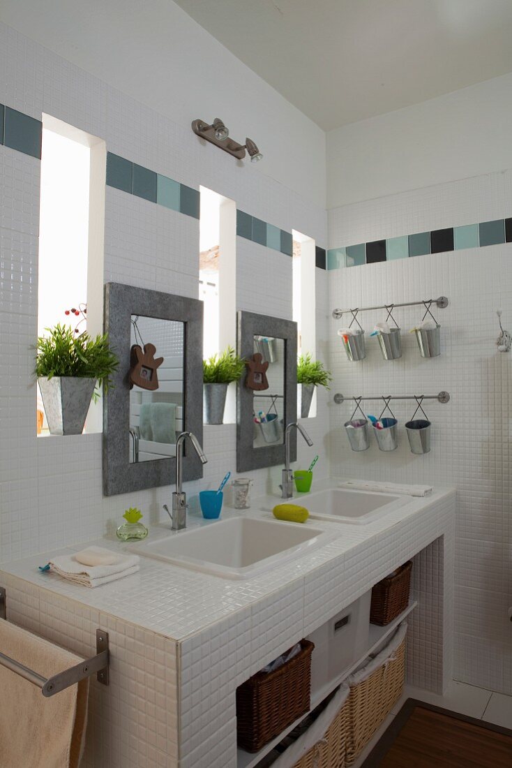 Weißer Waschtisch mit zwei Einbaubecken, Spiegel zwischen schmalen Fensteröffnungen an Wand in modernem Bad mit Fliesenbordüre