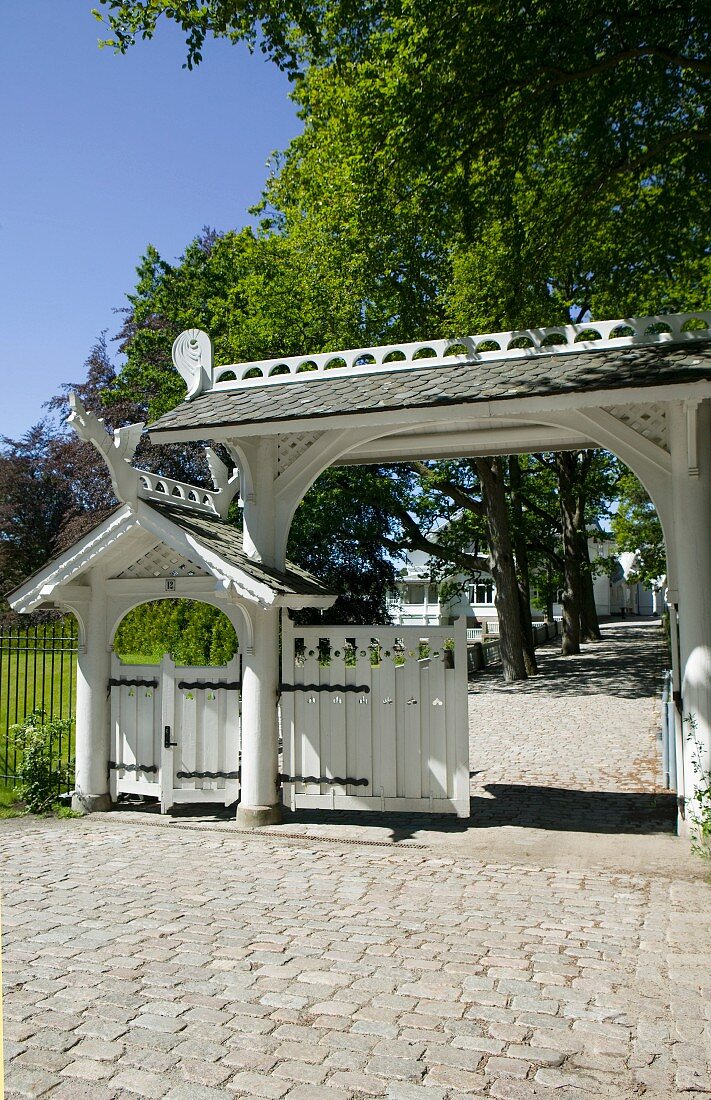 Paved drive with porch over wooden gate and pedestrian gate to one side
