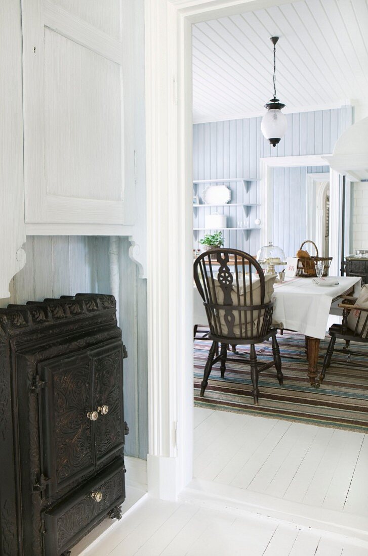 Blick von Diele mit eisernem Holzofen in Landhaus Wohnküche mit Windsor-Stühlen