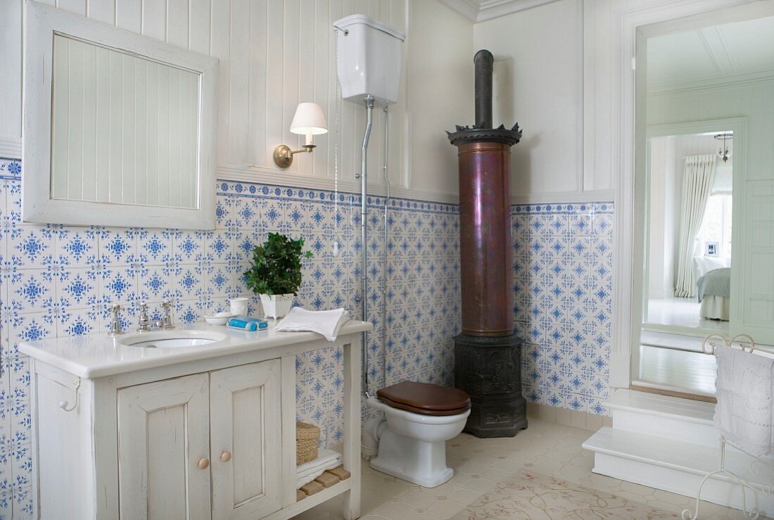 Traditionelles Badezimmer mit antikem Kanonenofen und blau-weissen Wandfliesen