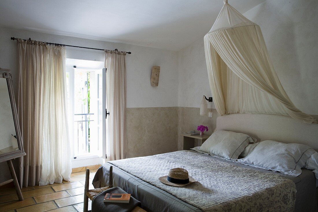 Weiche Naturfarben in Gästezimmer provenzalischen Stils mit Moskitonetz und gestepptem Überwurf (Boutis) auf Doppelbett