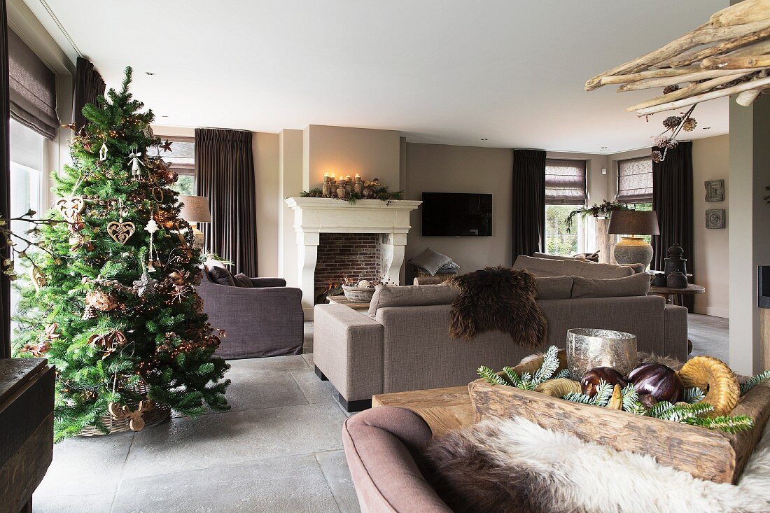 Decorated Christmas tree in open-plan interior with fireplace
