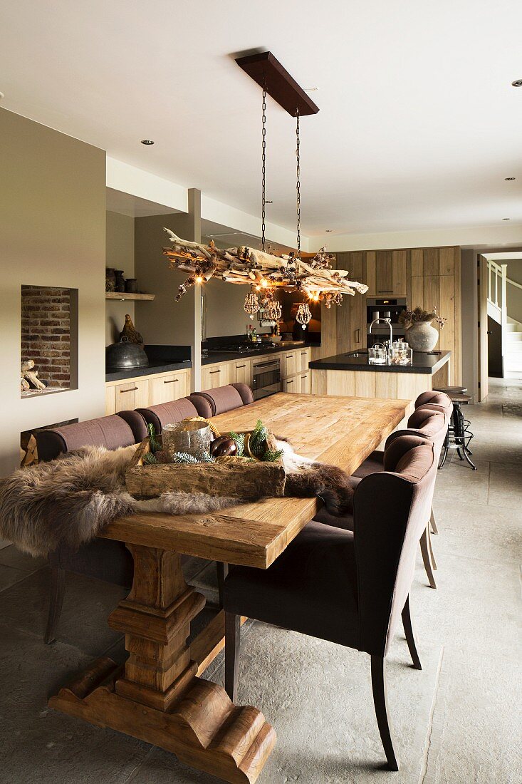 Rustikaler Massivholztisch und braune Polsterstühle in offenem Wohnraum mit verschiedenen Brauntönen