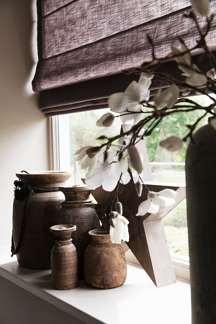 Ceramic vases of various sizes on windowsill; detail of flowering branch in vase in foreground