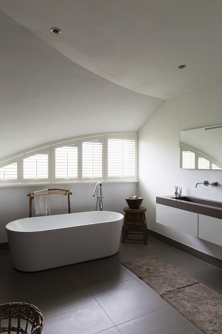 Free-standing bathtub in designer bathroom with vaulted ceiling and curved windows