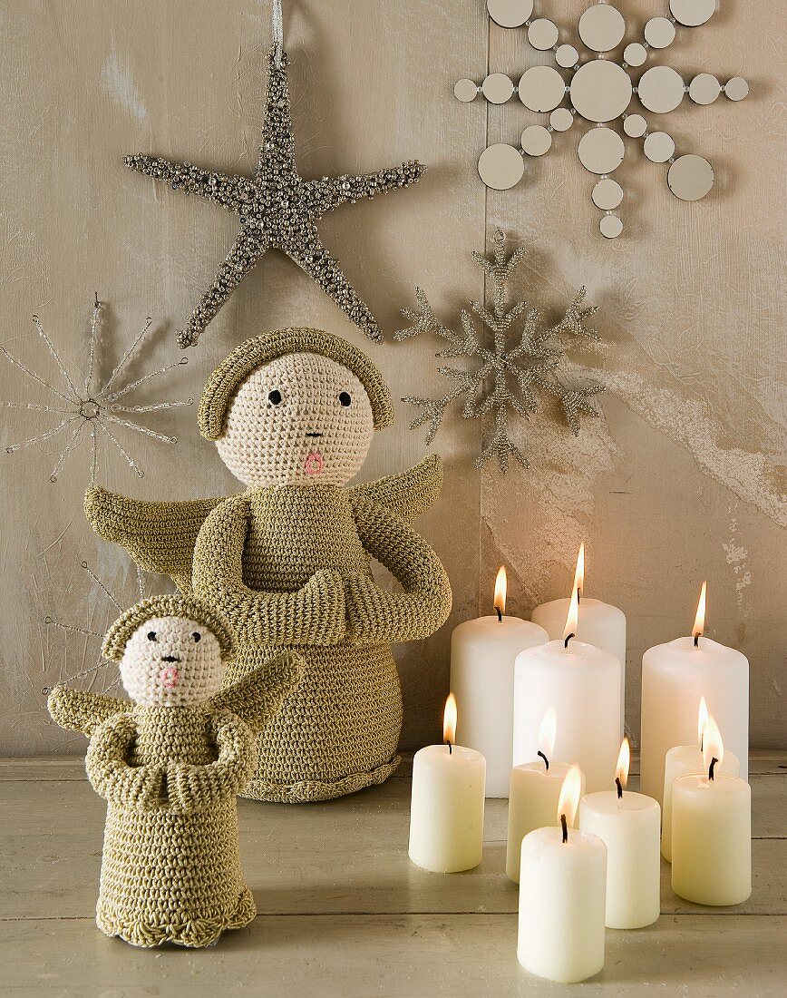 Weihnachtsdeko: Kerzen, gestrickte Engelsfiguren, an der Wand Sterne und Schneeflocken