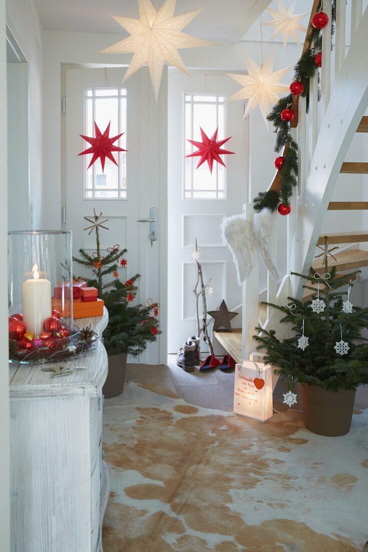 Weihnachtlich dekorierter Hauseingang mit geschmückten Tannenbäumchen und Girlande am Treppengeländer