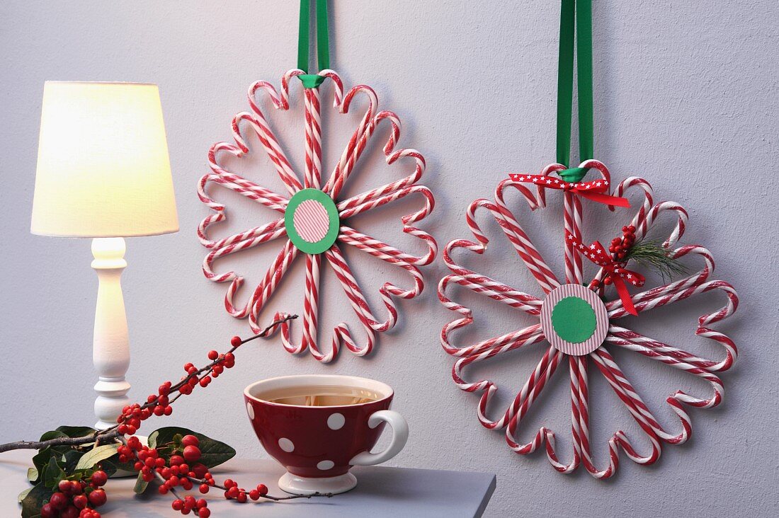 Zuckerstangen zu Herz-Kreisen zusammengeklebt und mit Schleifenband als weihnachtliche Deko an die Wand gehängt