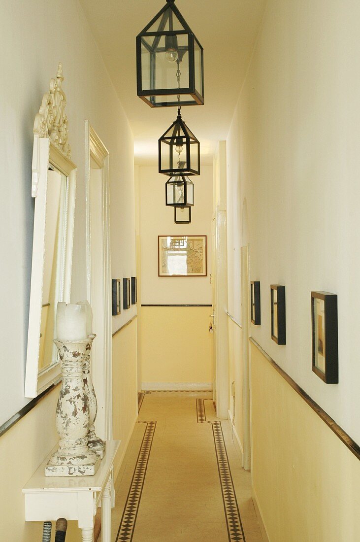 Long, narrow corridor in period apartment with row of lanterns hanging from ceiling