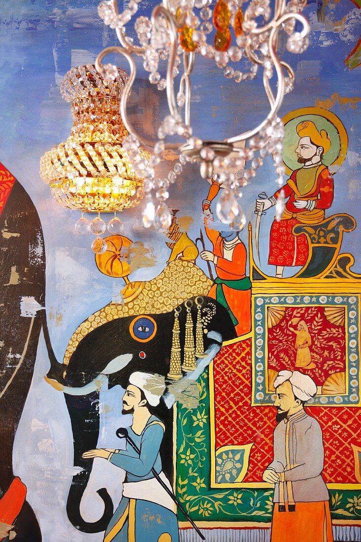 Chandelier in front of elephant caravan mural and crystal sconce lamp on wall