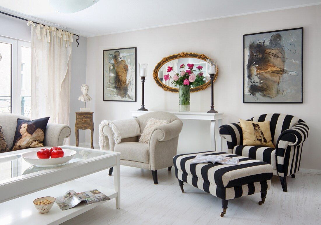 Heller, klassischer Wohnzimmer, Couchtisch mit Glasfüllung vor naturfarbenem Sessel und schwarzweiss gestreifter Fussschemel mit passendem Sessel