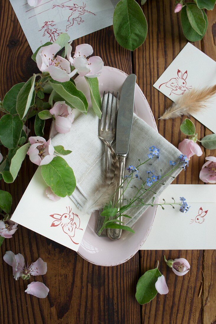 Silberbesteck in Schale mit Blüten und Tischkarten zu Ostern