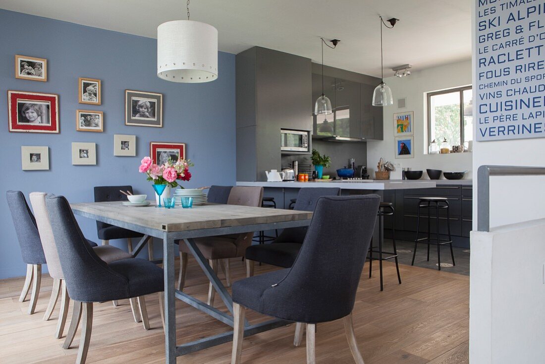 Open-plan kitchen-dining area in elegant shades of blue and grey decorated with family photos