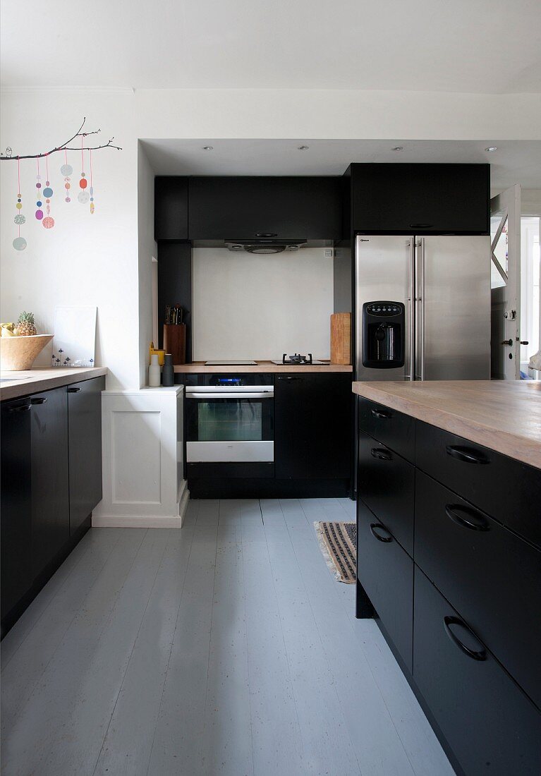Free-standing counter in kitchen with black fitted cupboards