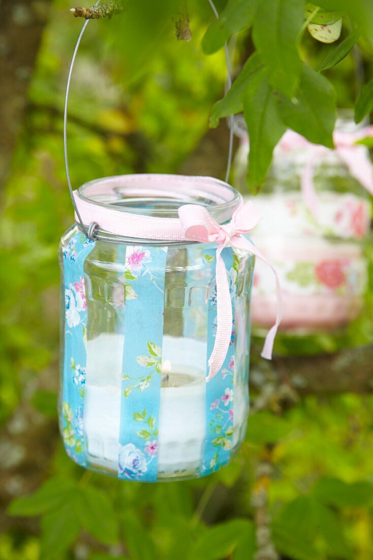 Tealight holder romantically decorated with pink ribbon hanging from branch