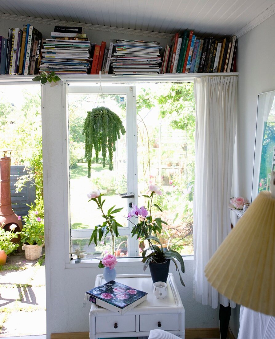 Stauraumlösung, Bücherboard über Terrassenfenster mit Blick in sommerlichen Garten