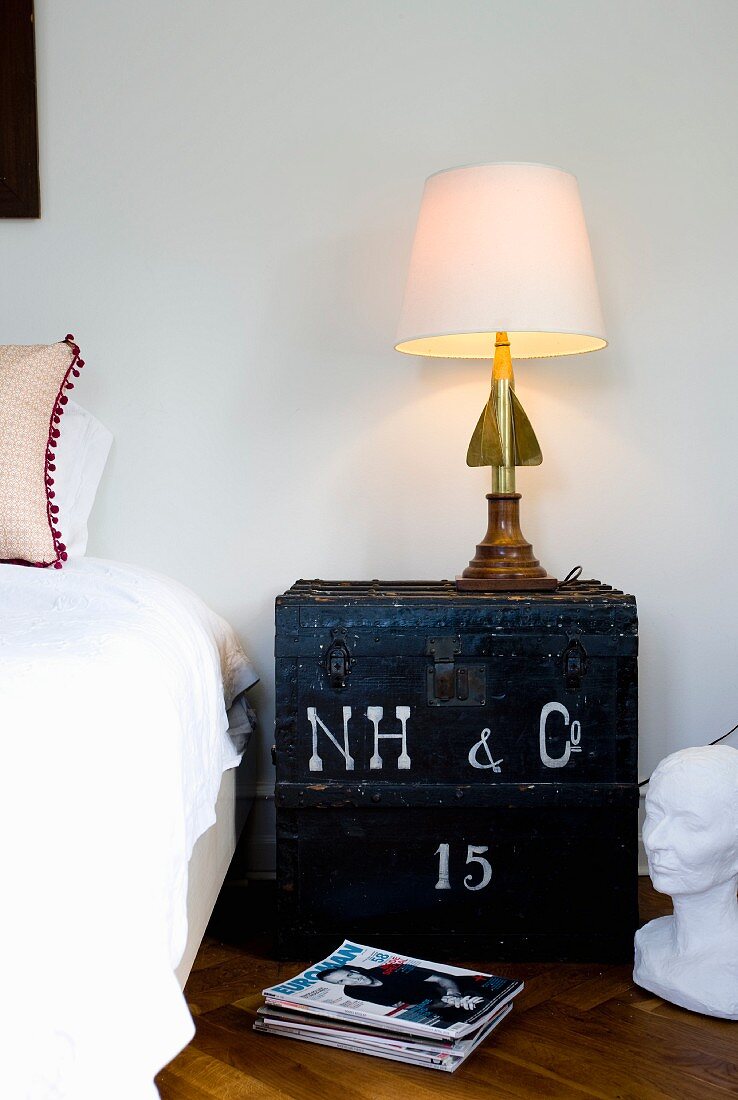 Eclectic table lamp on vintage wooden trunk used as bedside table