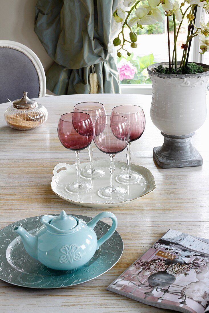 Red, smoked-glass wine glasses and teapot on dining table