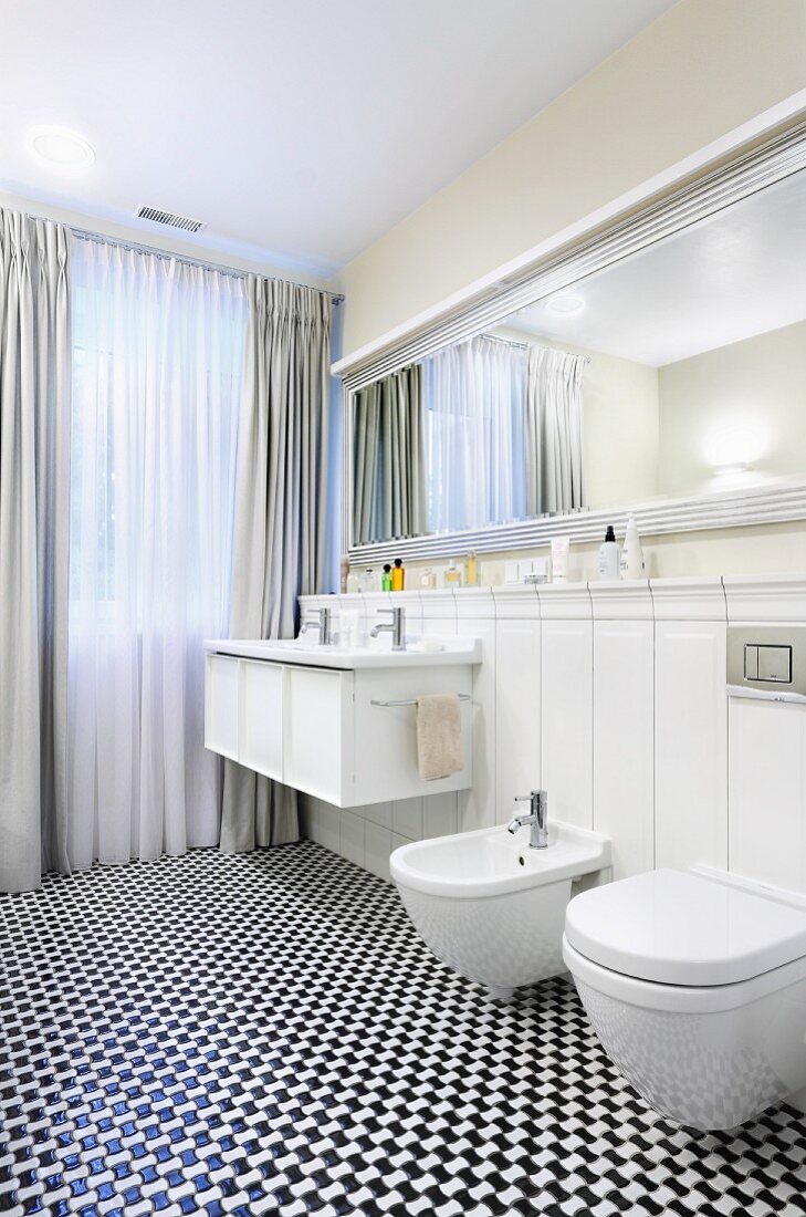 Schwarz-weisser Mosaikboden in elegantem Bad mit elegantem Spiegel und bodenlangen Vorhängen