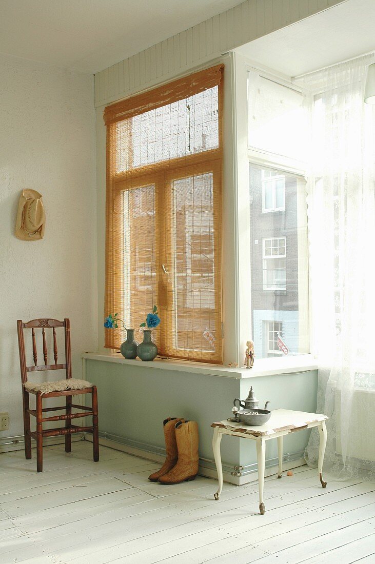 Alter Stuhl, Beistelltisch, Cowboystiefel und Zinndeko vor Fensternische