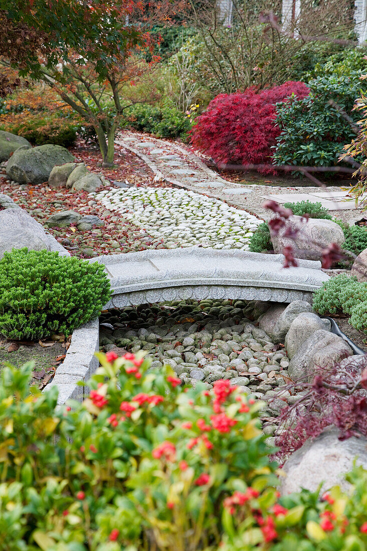 Stone bridge spanning gravel bed in Japanese-style garden