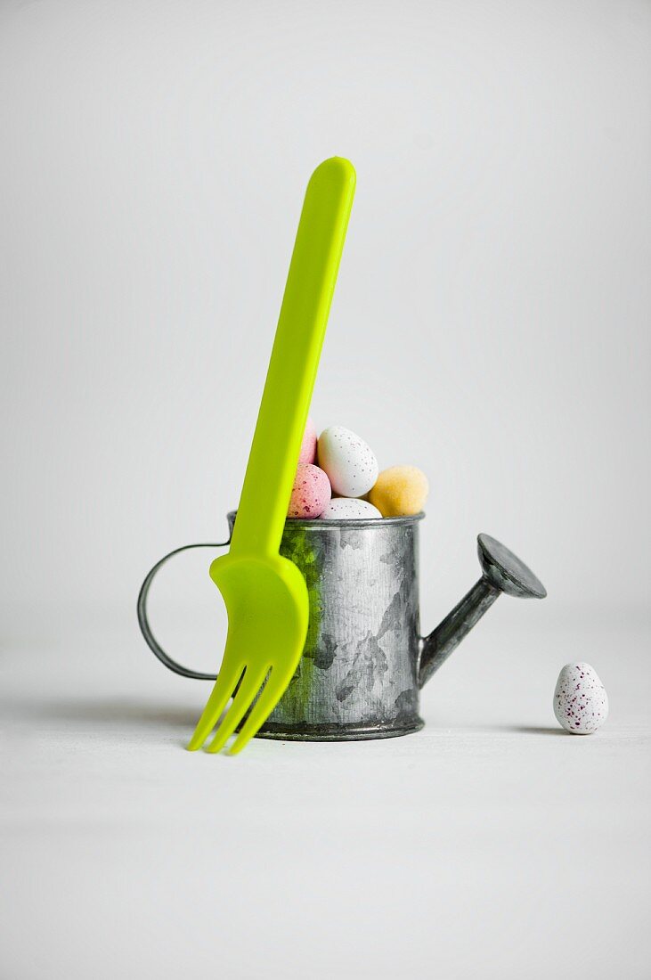 Pastel sugar eggs in a mini watering can and green fork