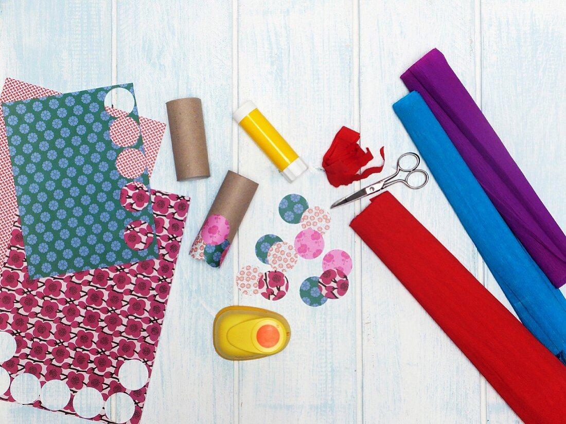 Utensils for crafting a wind chime: cardboard tubes, coloured paper, crepe paper and circle punch