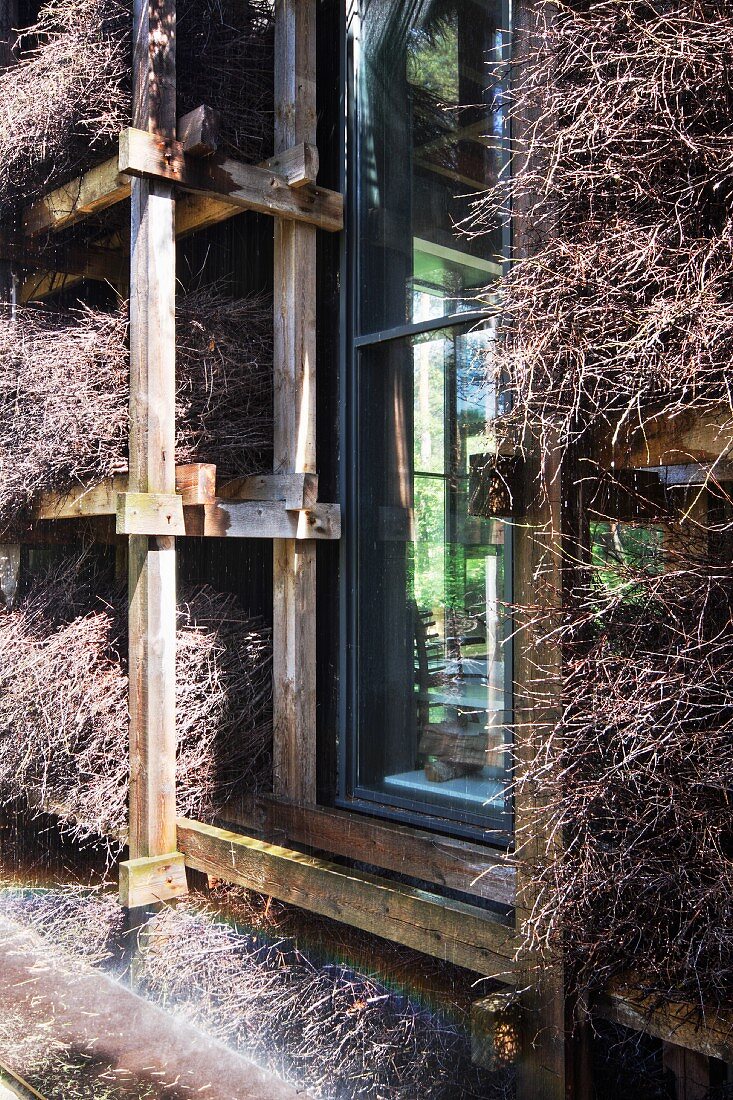 Bundles of brushwood against facade on wooden rack with aperture for window