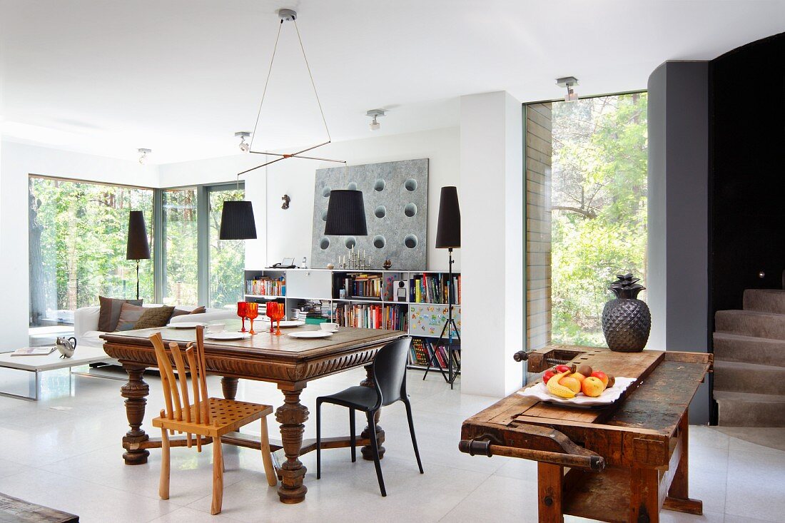 Dining area with antique table and workbench used as rustic kitchen counter in open-plan interior