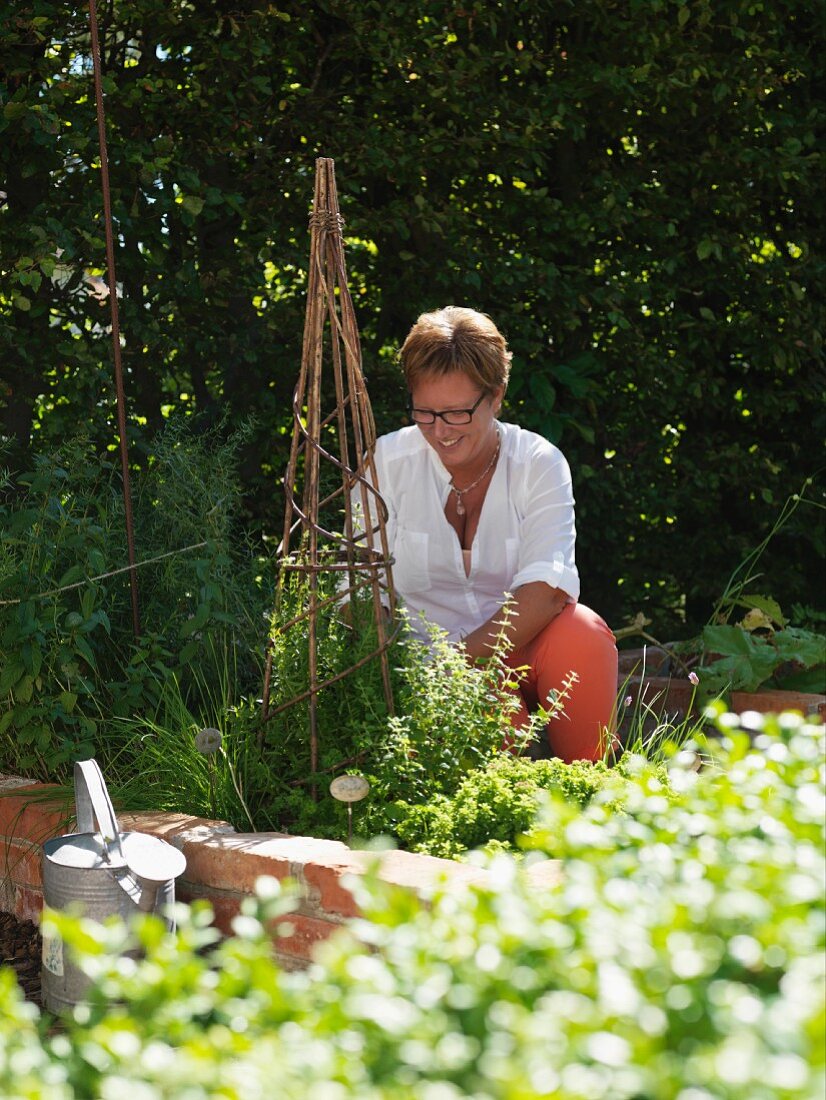 Frau bei Gartenarbeit, Rankhilfe aus Holzstäben