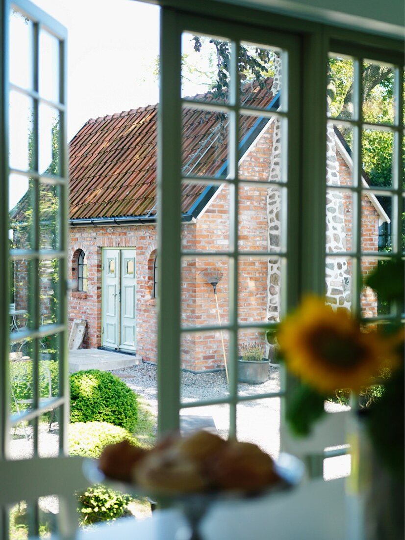 View of garden and small brick house through open French doors