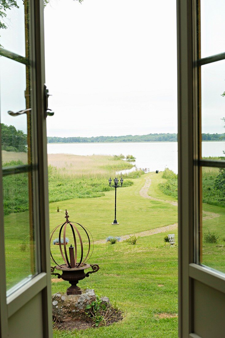 Blick durch offene Terrassentüren auf Wiese und den angrenzenden See