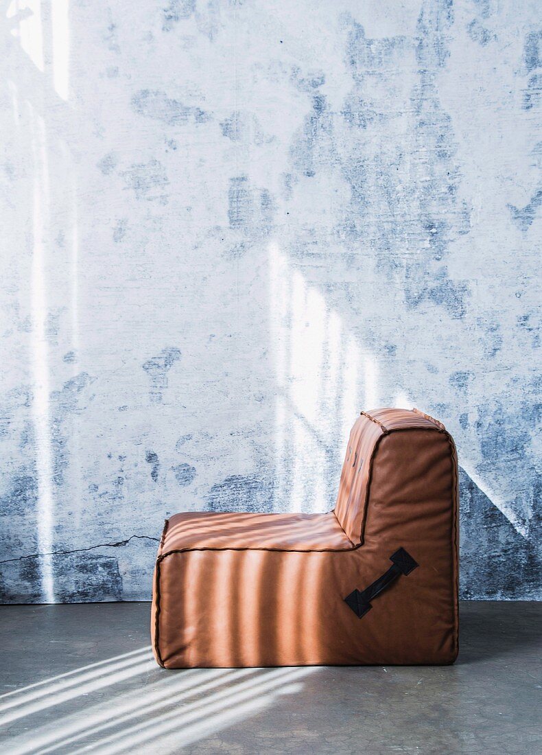 Brown leather modular armchair against wall