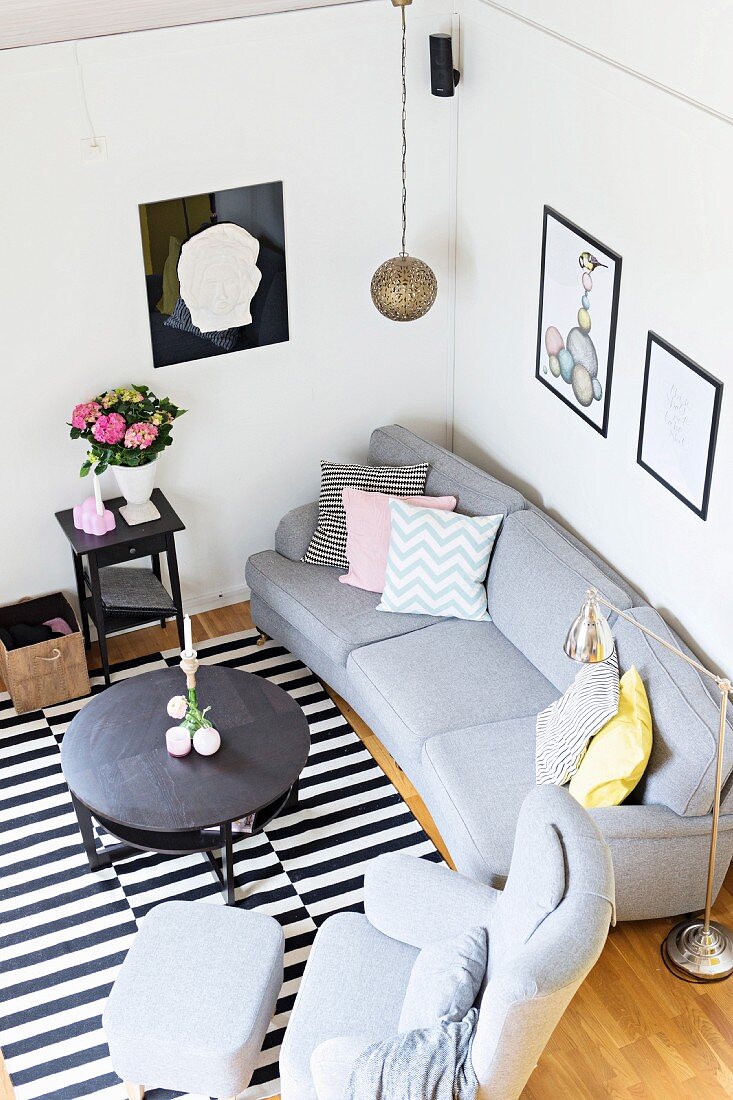 View down onto grey sofa set, round coffee table and black and white striped rug in corner of living room