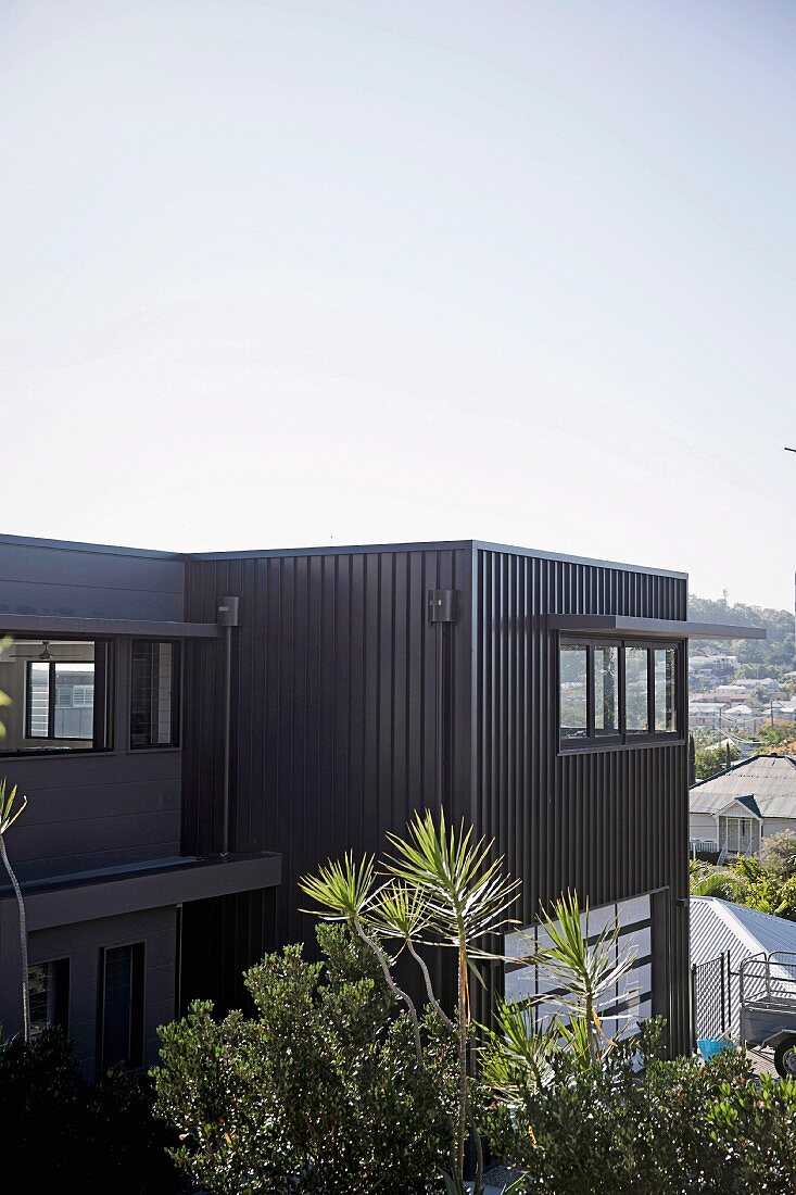 Charcoal-grey metal façade of modern, cubist house with view over Brisbane, Australia
