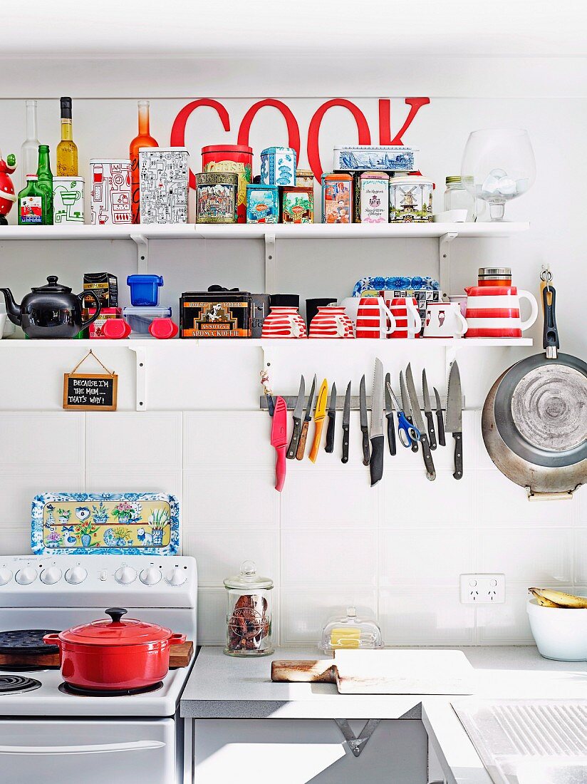 Collection of tins on kitchen shelf and magnetic knife rack in simple, retro-style kitchen